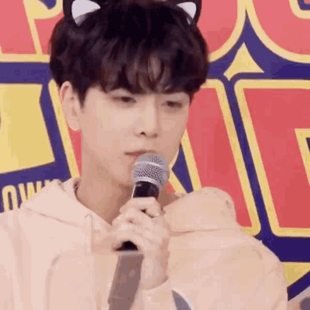 a young man with cat ears is holding a microphone