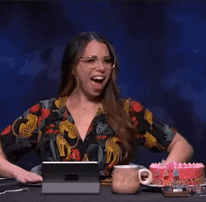 a woman in a floral dress is sitting at a table with a tablet and a cake .