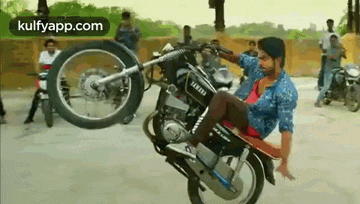 a man is doing a wheelie on a motorcycle on a street .