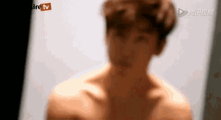 a man without a shirt is standing in front of a camera .