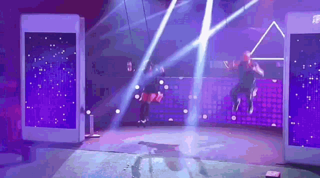 a group of people on a stage with purple lights