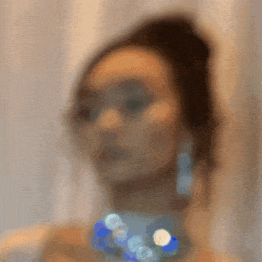 a blurry picture of a woman wearing a necklace and earrings