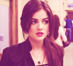 a woman wearing a black jacket and a necklace with a pendant that says ' s ' on it