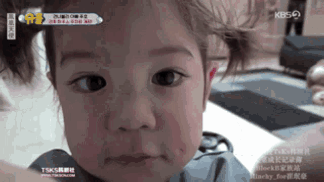 a close up of a baby 's face with the kbs logo on the bottom
