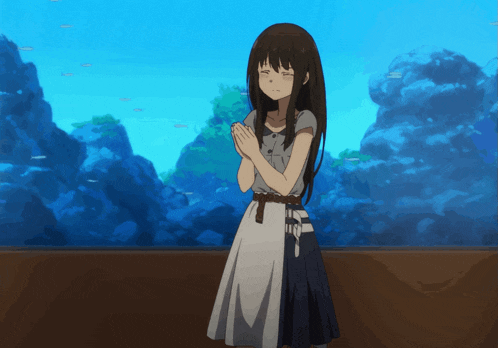 a girl praying in front of an aquarium with fish in it