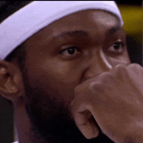a man wearing a white headband is covering his mouth with his hand