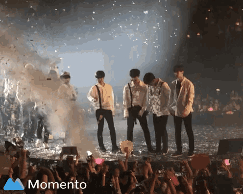 a group of people standing on a stage in front of a crowd and a momento logo