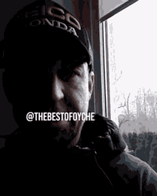 a man wearing a seiko honda hat is looking out a window