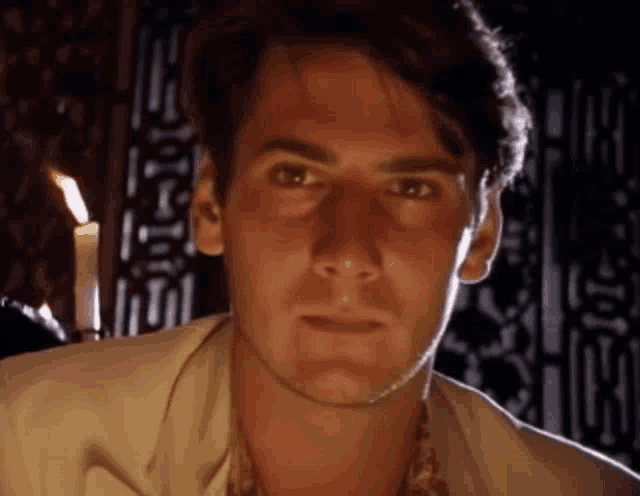 a close up of a man 's face with a candle behind him