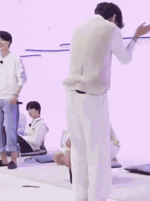 a man in a white vest and white pants is standing in front of a group of people