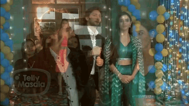 a group of people are standing in front of balloons and a telly masala sign