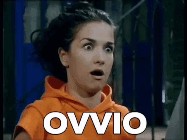 a woman with a surprised look on her face is wearing an orange sweatshirt with the word ovvio written on it