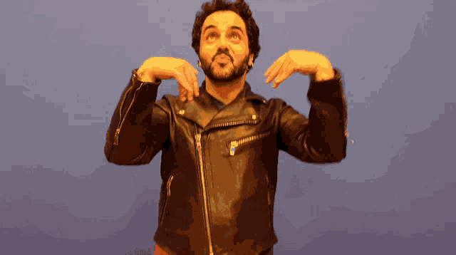 a man in a leather jacket is making a funny face with his hands