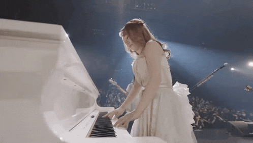 a woman in a white dress is playing a white grand piano