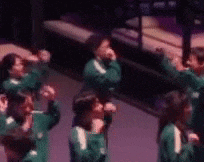a group of people are standing in a room with their hands up in the air .