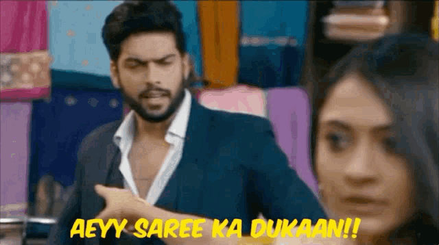 a man in a suit is pointing at a woman and says aeyy saree ka dukaan !