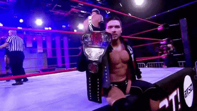 a man is holding a wrestling championship belt in a wrestling ring .