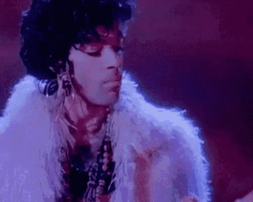 a close up of a man wearing a white fur coat and earrings .
