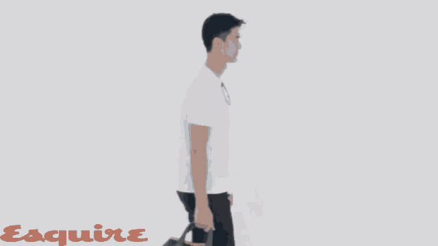 a man carrying a blue tote bag with the word esquire on the bottom right