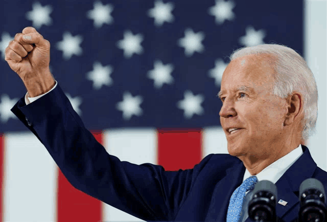 a man in a suit and tie holds his fist up in the air