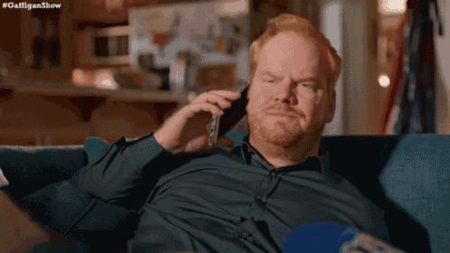 a man is sitting on a couch talking on a cell phone