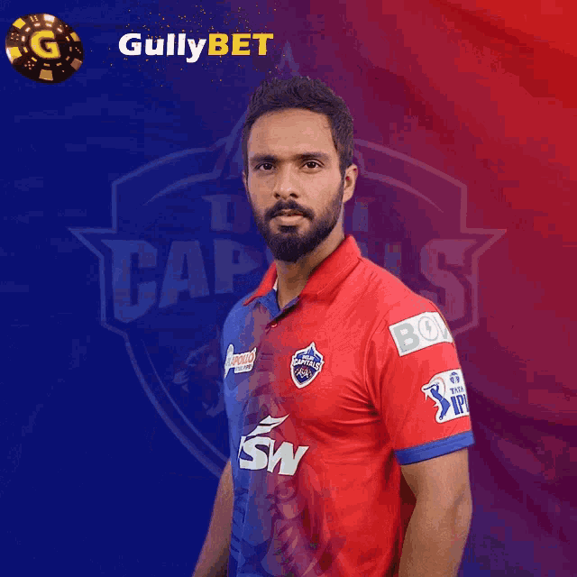 a man in a red and blue shirt stands in front of a delhi capitals logo