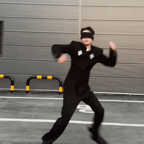 a man wearing a blindfold and a black suit is dancing