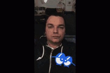 a man taking a selfie with a blue sticker on his chest that says ' squid '