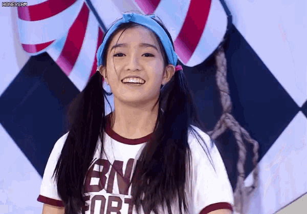 a young girl wearing a bn fort shirt smiles