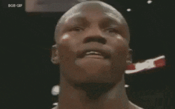 a group of men are standing around a man in a boxing ring