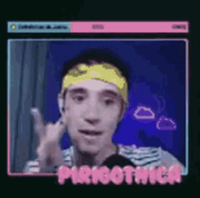 a man wearing a yellow headband is giving a peace sign while talking into a microphone .