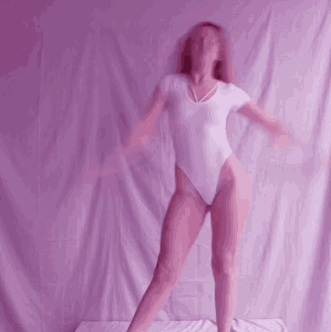 a woman in a white leotard is dancing in front of a purple background .