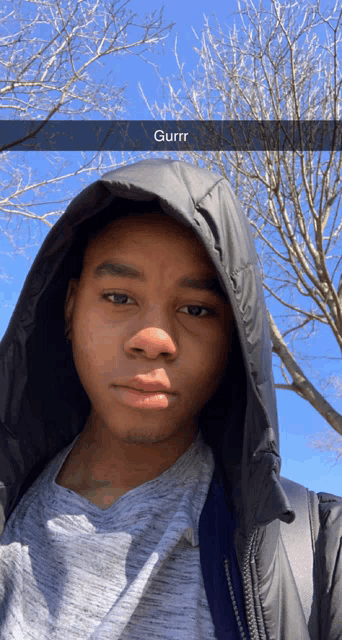 a young man wearing a hooded jacket is taking a selfie with a caption that says gurr