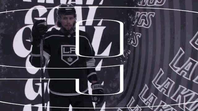 a hockey player stands in front of a wall that says la