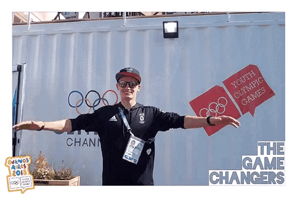 a man with his arms outstretched in front of a sign that says youth olympic games
