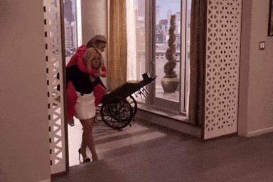 a woman carrying another woman in a wheelchair