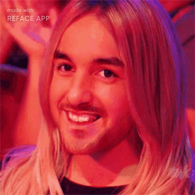 a man with long blonde hair and a beard smiles for the camera