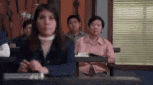 a woman is sitting in a classroom with other people .