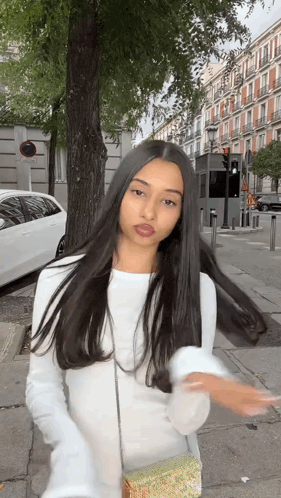 a woman with long black hair is standing in front of a tree