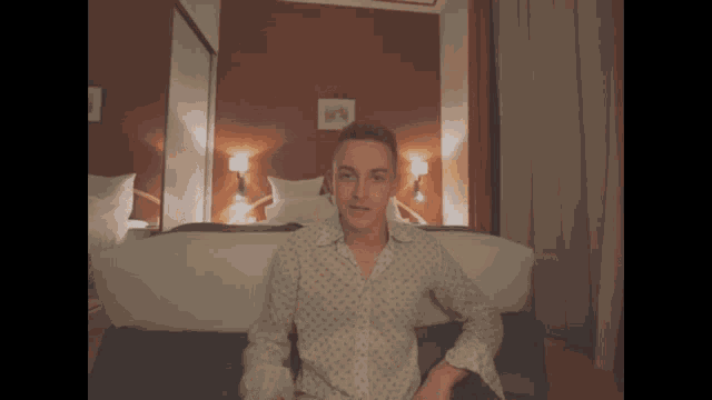 a man sitting on a bed making a rude gesture