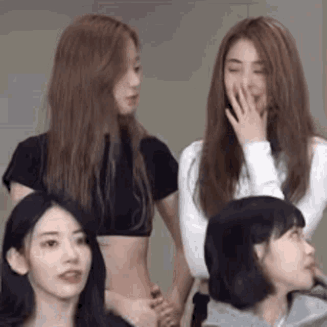 a group of young women are standing next to each other and one of them is covering her mouth .