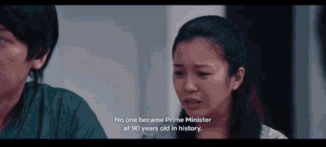 a woman in a hospital gown talks to a man and says " no one became prime minister at 90 years old in history "
