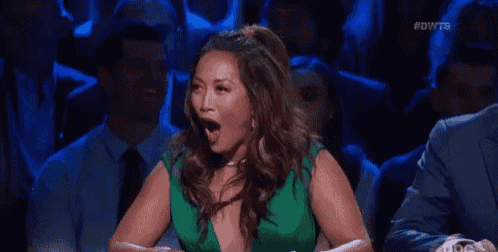 a woman in a green dress is laughing with her mouth open in front of a crowd .