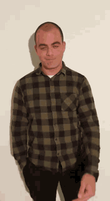 a man wearing a plaid shirt is standing with his hands in his pockets