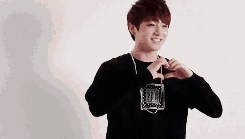 a young boy is making a heart shape with his hands while wearing headphones .