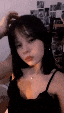 a girl in a black tank top is taking a selfie in a bedroom .