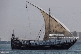 a large sailboat with a large sail is floating on top of a body of water .