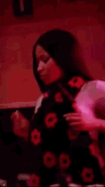 a woman is smoking a cigarette in a dark room with pink lights .