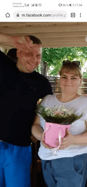 a man and a woman are standing next to each other holding a pink box of flowers