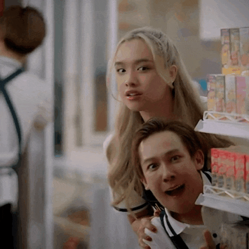 a man and a woman are standing next to each other in a store looking at something .